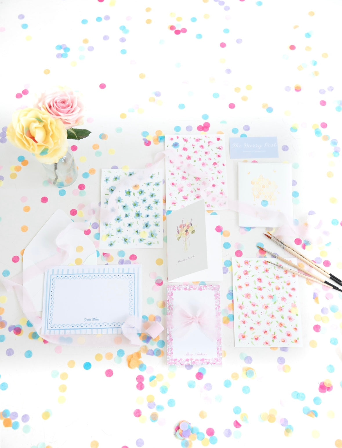 The Merry Post stationery flat lay with greeting cards, stationery sets, and confetti